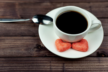 Two hearts on a saucer with coffee. Dark wooden background with a place for an inscription.