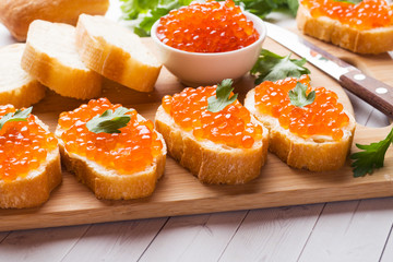 Naklejka na ściany i meble Sandwiches with red salmon caviar on a wooden Board. White table top.