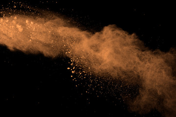 abstract brown powder splatted background. Colorful powder explosion on black background. Colored...