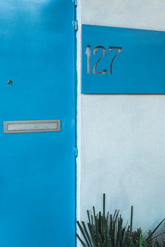 Blue wall of residential building with simple tablet showing number of house 127 in neighborhood of Mexico city