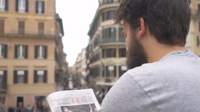 Man Reading Newspaper. Busy Cityscape In The Background.