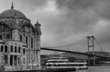 Fototapeta na wymiar Istanbul, Turkey. 06-December-2018. Scenic black and white photo of Ortakoy mosque and bridge during a cloudy day