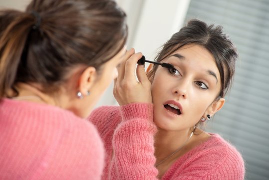 Young Brunette Woman Putting Makeup In The Mirror