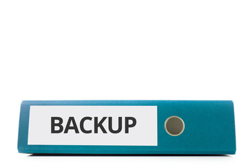 blauer liegender Aktenordner mit Beschriftung Backup vor hellem Hintergrund