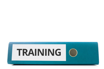 blauer liegender Aktenordner mit Beschriftung Training vor hellem Hintergrund