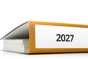 oranger Aktenordner gefüllt mit Papierseiten und Beschriftung 2027 liegend vor weißem Hintergrund