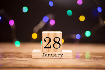 January 28th. Day 28 of month at center of dark background with garland bokeh. Winter time, year concept.