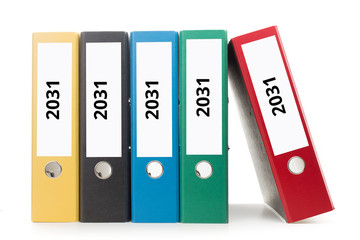 mehrere bunte Aktenordner dessen Ordnerr&uuml;cken beschriftet sind mit 2031 stehend vor hellem Hintergrund