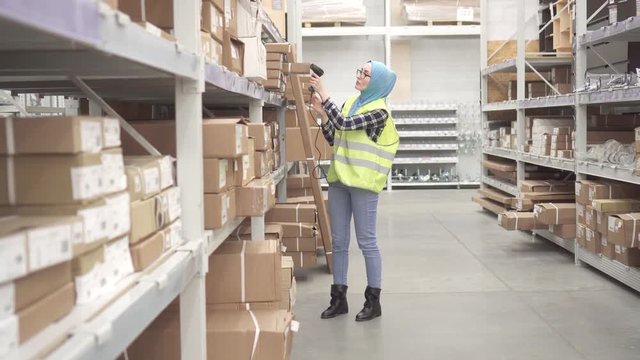 Muslim in a hijab holds inventory with barcode scanner