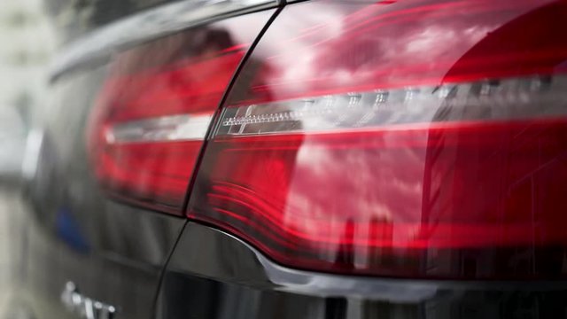 Close up of red tail lights, detail of modern, luxury, black SUV. Stock. Black car break lights, automotive lighting concept.