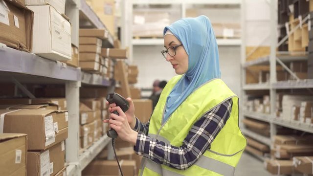 Muslim in hijab shop worker with barcode scanner