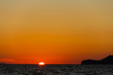 The sun is hiding the beach edge with orange sky