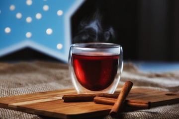 Glass Cup of delicious hot mulled wine on a wooden Board with cinnamon sticks