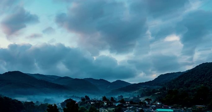 time-lapse morning scene of the mountain with village and motion cloudy sky in the background.