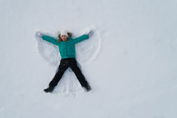 Fototapeta na wymiar Girl on the snow shows an angel View from above