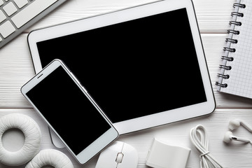 White modern digital tablet and smartphone, headphones, computer mouse and keyborad on white background