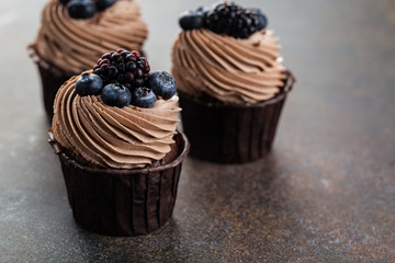 Various sweet chocolate cupcakes on brown stone background. 