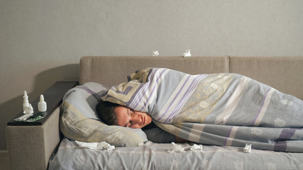 Sick man lying under blanket