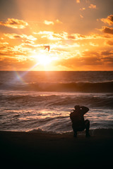 Fototapeta premium silhouette of a photographer on the beach at sunset
