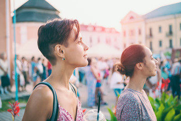 Two girls are watching a street concert.