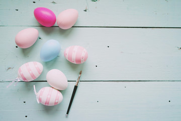 A beautiful and colorful close-up flat of isolated easter eggs in plain colors and striped by a small brush over a pastel blue wooden table with space