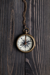 Old vintage metal compass on wooden table