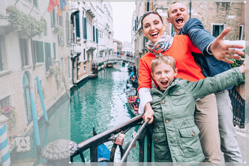 Fototapeta na wymiar Madly happy family take a selfie photo on the one of bridge in Venice. Travel around the wolrd with kids concept image