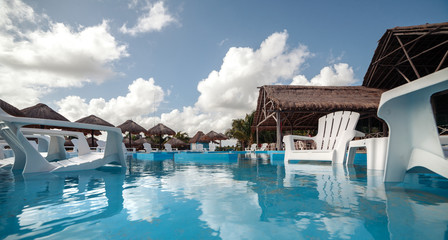 Pool, lounge chairs and canopies of palm leaves on the ocean. Mexico. Cancun. Cozumel