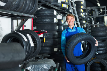 Fototapeta na wymiar Portrait of mechanic man with auto tires in workshop