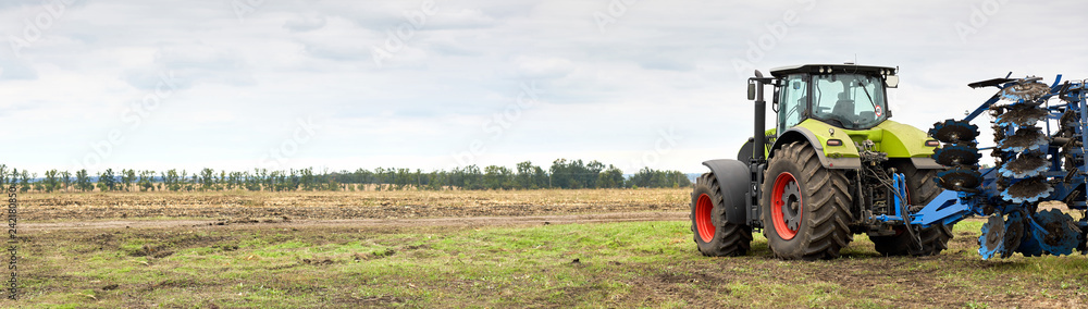 Aufkleber Tractor working in a field against a cloudy sky