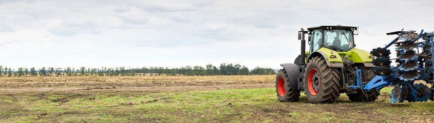 Tractor working in a field against a cloudy sky