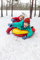 Boy and girl sliding on snow tubing