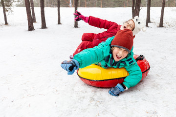 Boy and girl sliding on snow tubing