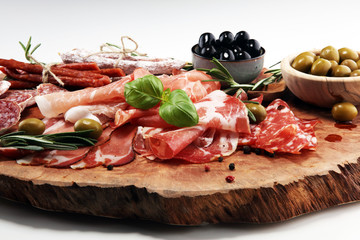 Marble cutting board with prosciutto, bacon, salami and sausages on wooden background. Meat platter