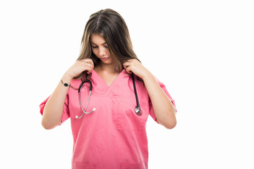 Portrait of beautiful young doctor wearing scrubs arranging stethoscope