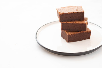 Chocolate brownie square pieces in stack on white plate. American traditional delicious dessert....