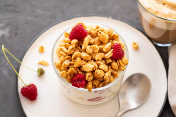Fresh yoghurt with rasberries and coffee in clear glass. Raspberries in white bowl. Healthy morning breakfast.
