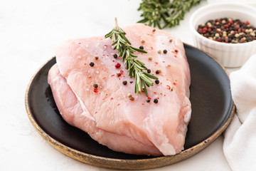 Turkey breast raw meat with spices on a dark background. Copy space.