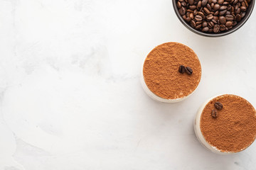 Traditional Italian dessert tiramisu in a glass on a white stone background. Copy space.