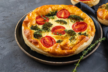Vegetable pie with broccoli, tomatoes on the table close-up. Copy space.
