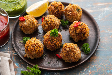 Homemade meatballs with thyme and green sauce on a black plate. Copy space.