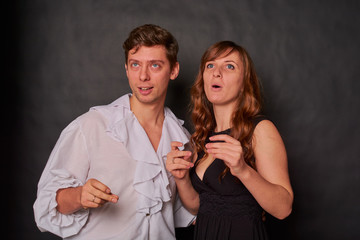 a guy and a girl stand and sing against