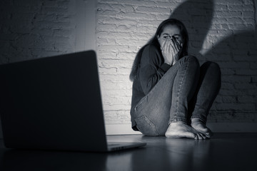 Woman suffering Internet cyber bullying and harassment feeling lonely looking afraid at laptop