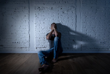 Desperate lonely caucasian man suffering from depression sitting alone on floor at home