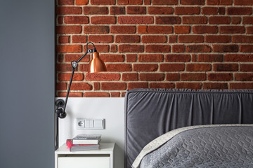 Photo of small bedroom with gray couch and brick wall