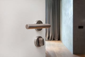 Open white door with metallic handle. The door to the bedroom