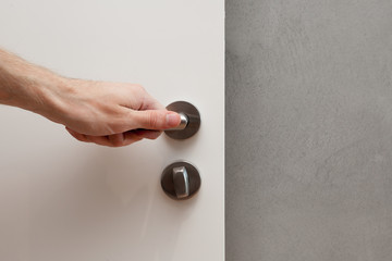 Naklejka premium Close white door with metallic handle. The man opens the door