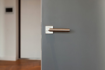 New door with metallic handle open in to the room. Focus on the handle