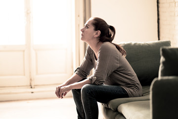 Young woman suffering from depression feeling sad and lonely on sofa at home