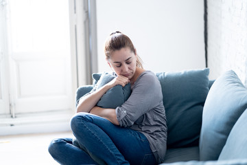 Young woman suffering from depression feeling sad and lonely on sofa at home